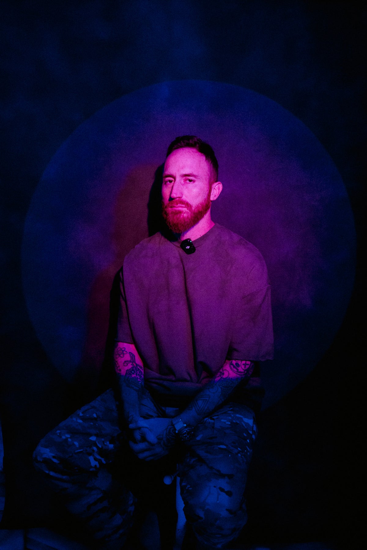 CALMA artist Carlos Alberto Lopez seated in purple and blue studio lighting.